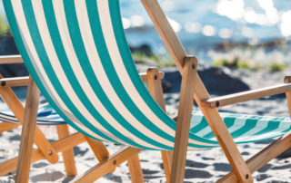 Ein Liegestuhl steht im Sand am Meer.