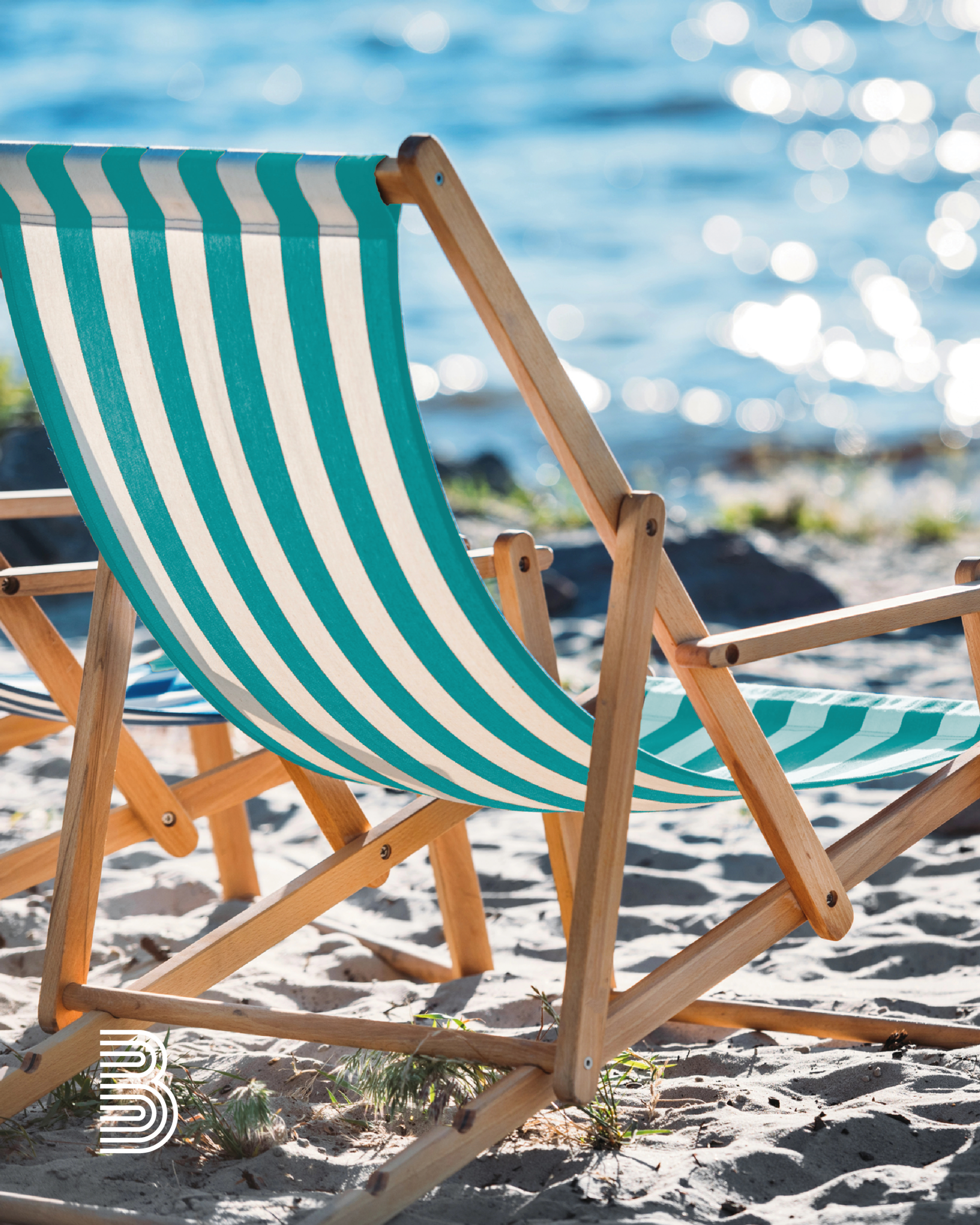 2025_07_sommer_zeichenfla_che_1 Ein Liegestuhl steht im Sand am Meer.