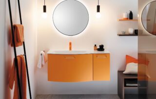 Ein orangefarbener Waschtisch mit rundem Spiegel und Badezimmereinrichtung.