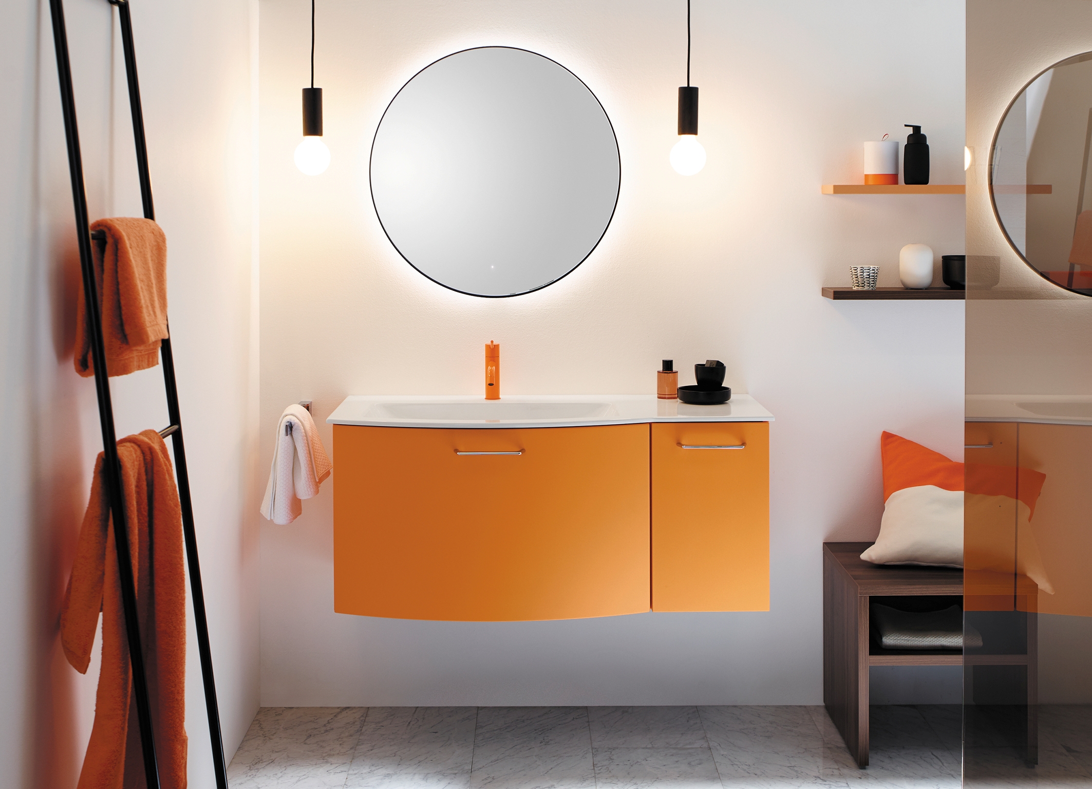 2202_4690_vds_burgbad_diago Ein orangefarbener Waschtisch mit rundem Spiegel und Badezimmereinrichtung.