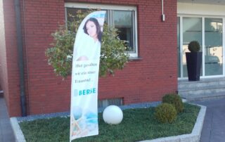 Eine Beachflag von der Berse GmbH steht vor einer Haustür, um zu zeigen, dass hier ein neues Bad entsteht.