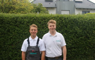 Jannik Bresser und Dennis Milowanowic stehen vor einer grünen Hecke.