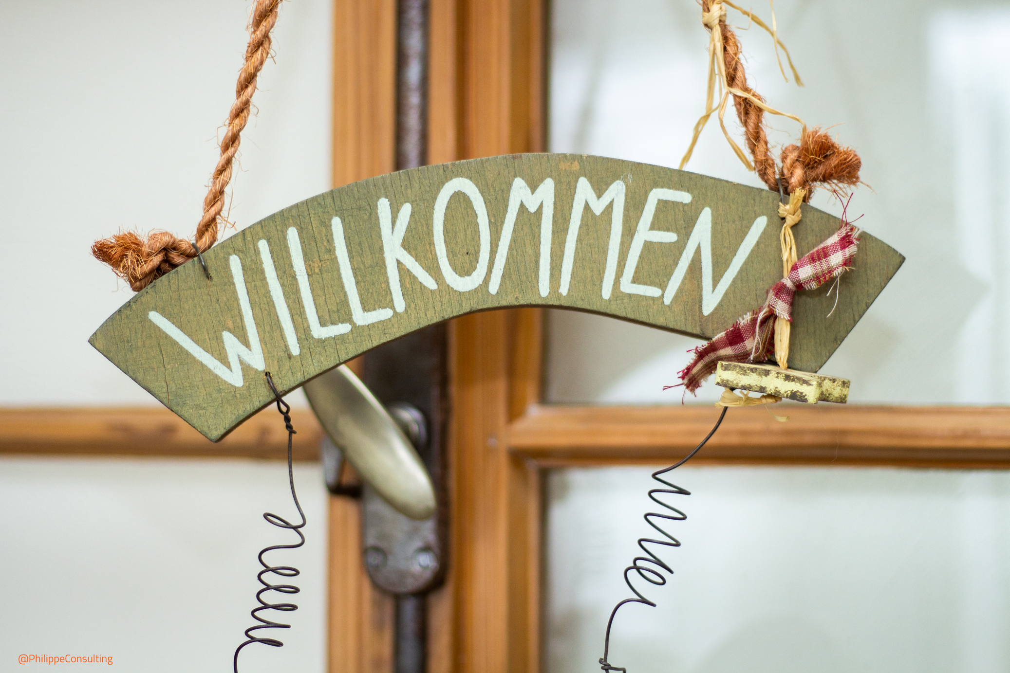 Ein Schild mit der Aufschrift "Willkommen" hängt an einer Tür.