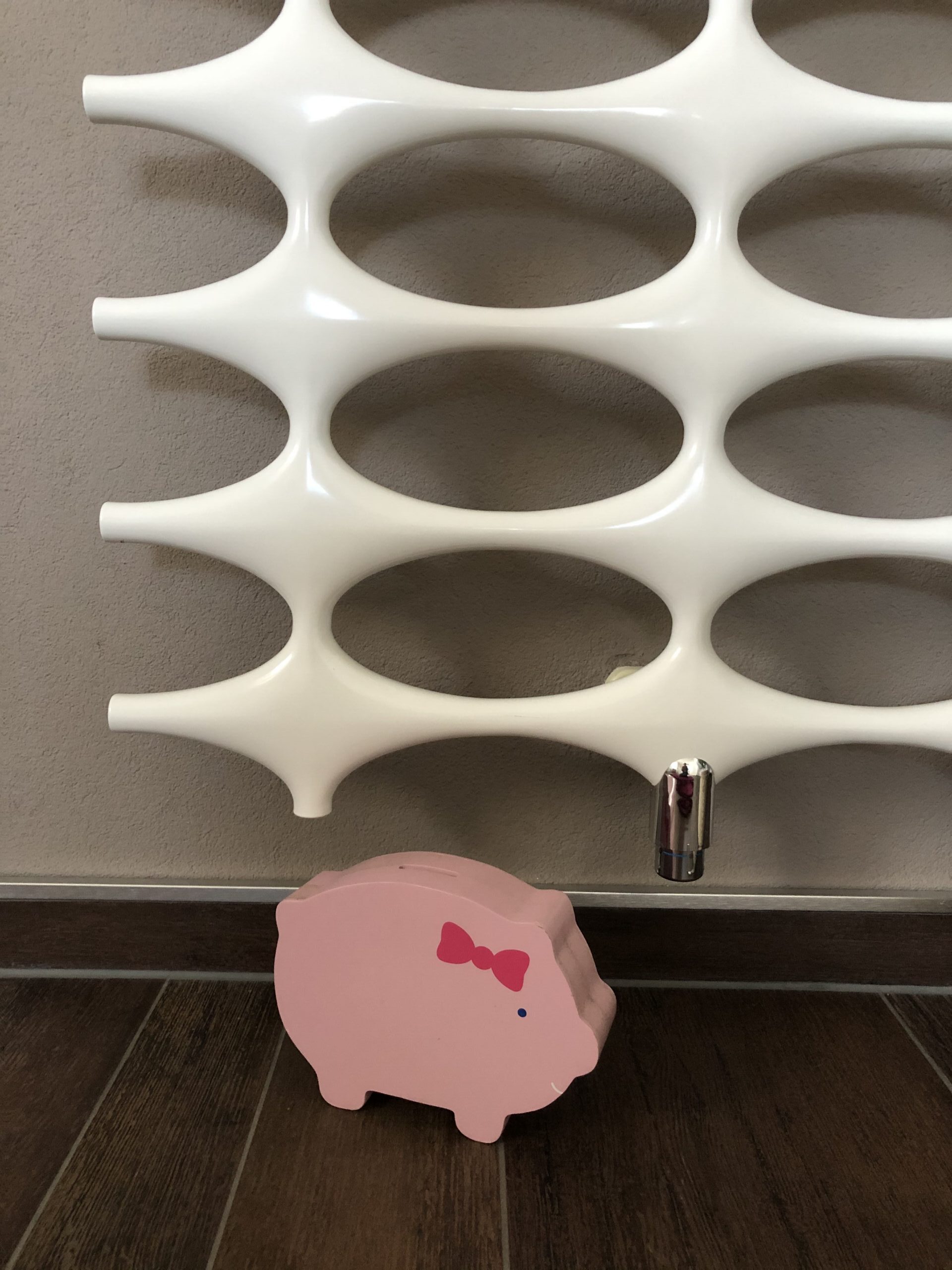 sparschwein_heizka_rper Ein Sparschwein steht unter einem Heizkörper.