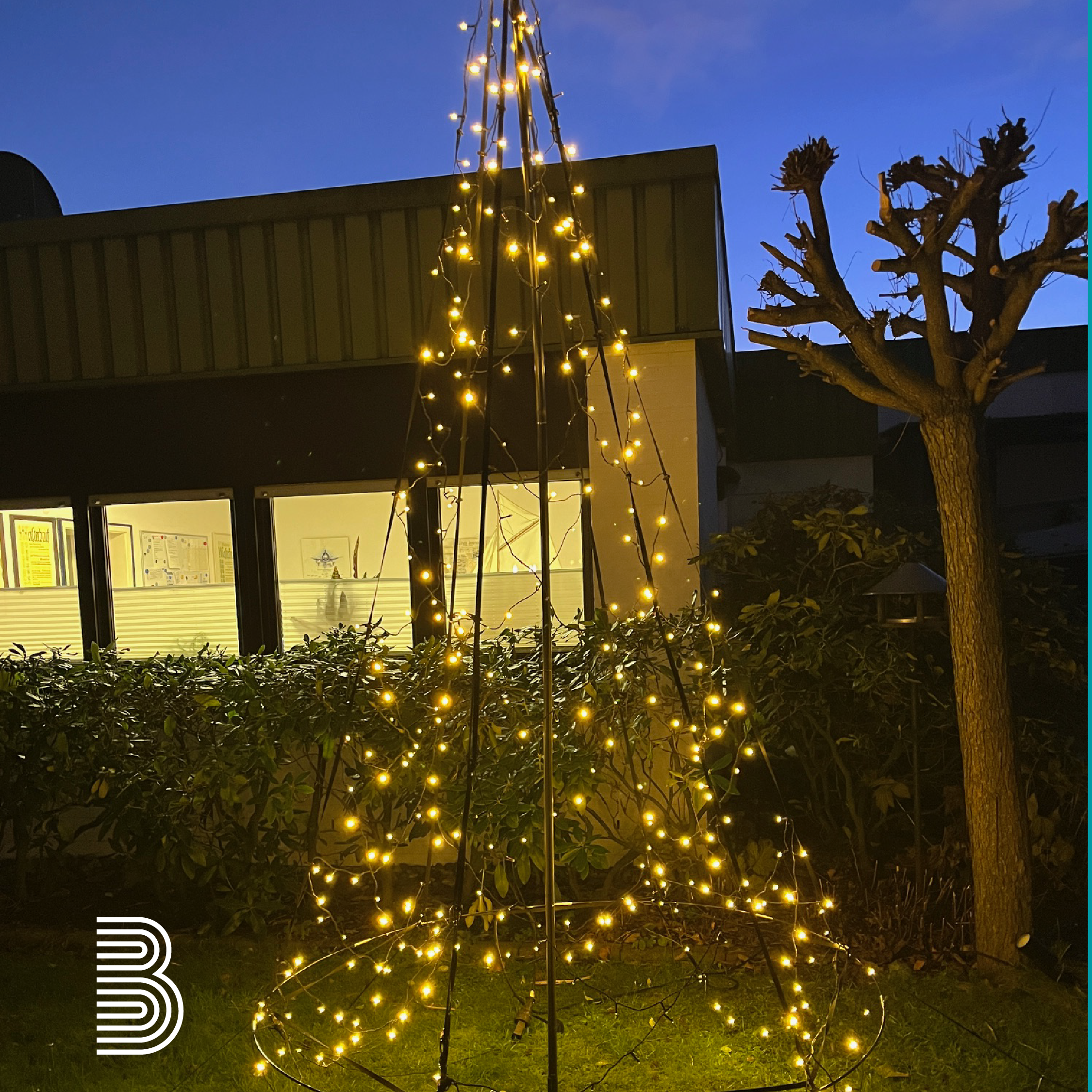 xmas Ein Baum aus Lichtern steht in der Dunkelheit vor einem Haus.